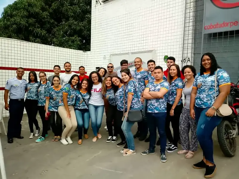 Turma de camisa azul estampada reunida para a foto em frente a um muro de azulejo